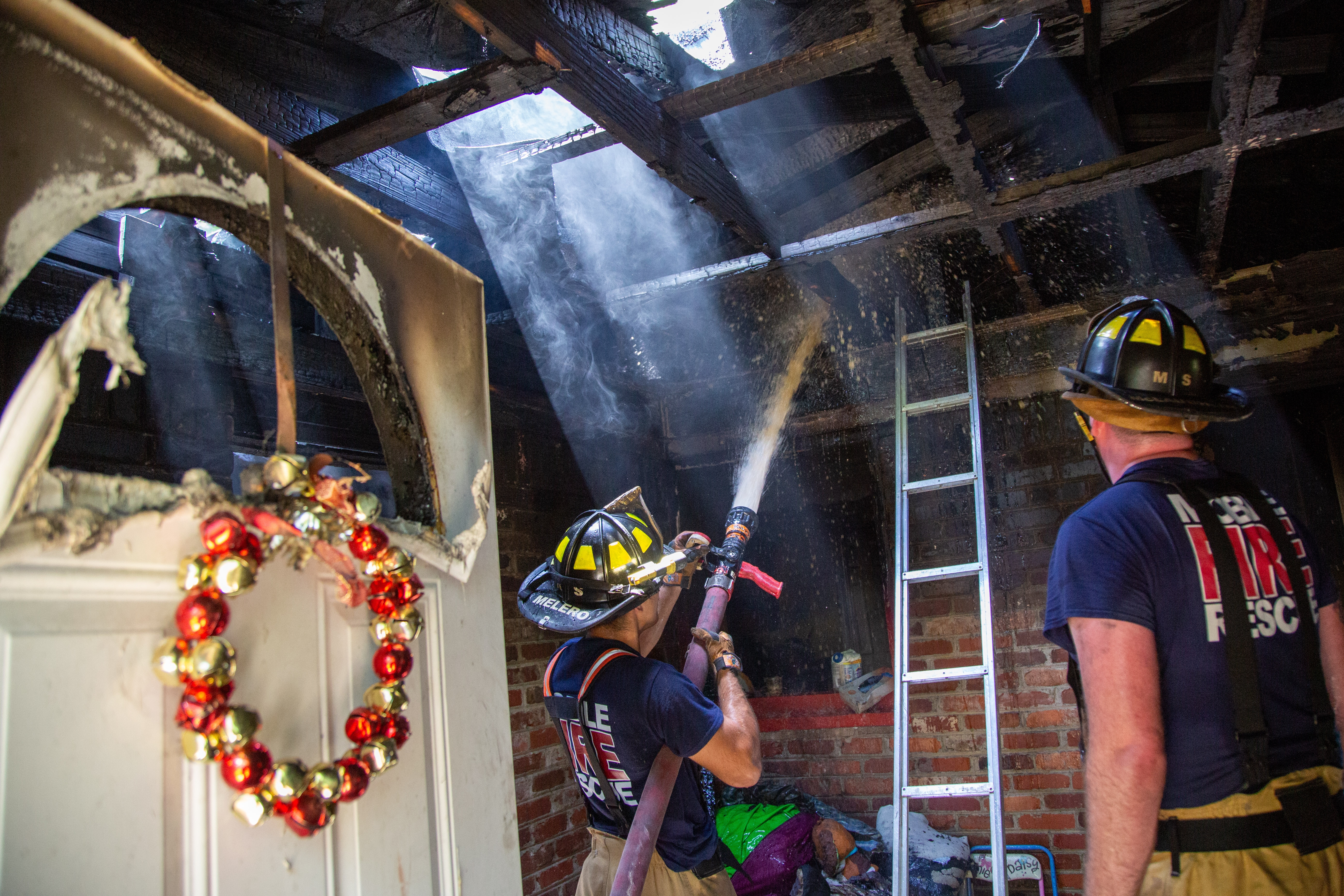 Firefighters extinguish residential fire hotspots.