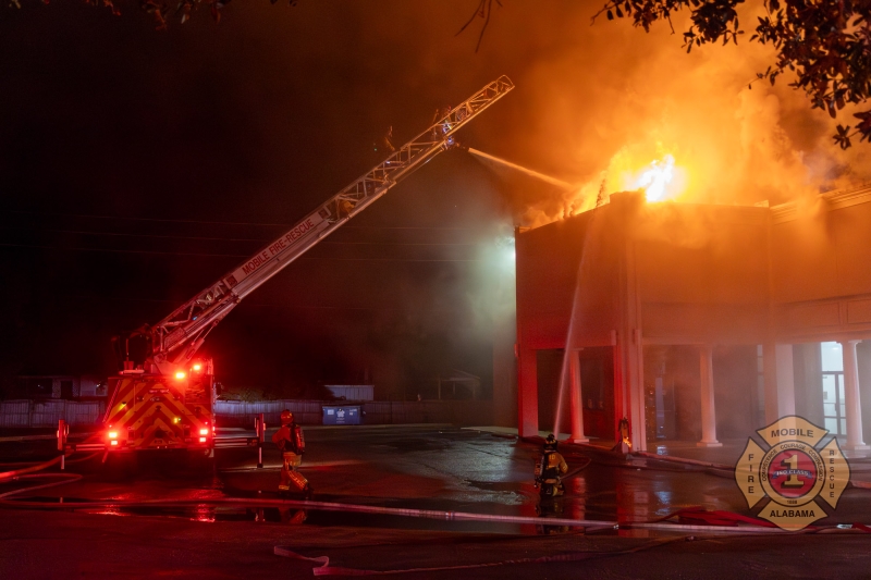 Mobile Fire-Rescue Department firefighters work to stop a three-alarm commercial building fire in a strip mall in the 5600 block of Old Shell Road Saturday night, September 30, 2023.